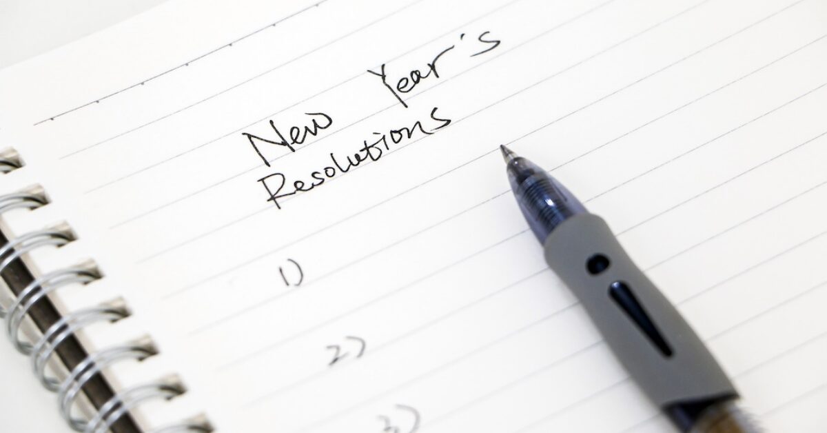 Writing new year’s resolutions, list on white notepad with ballpoint pen. Setting goals for the new year.