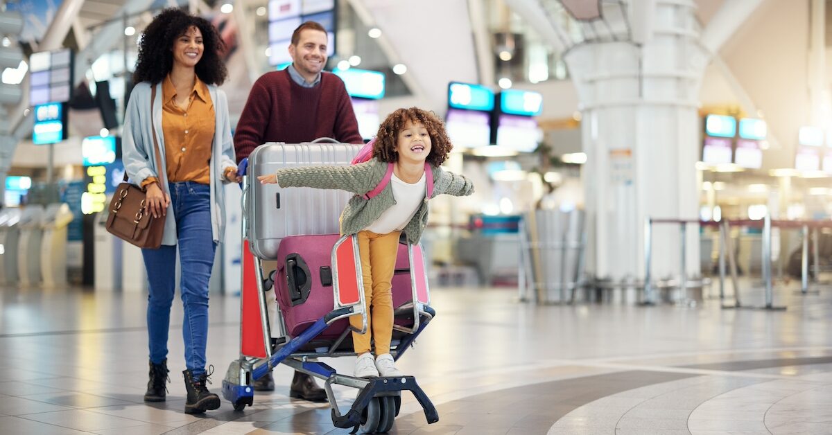 Airport, family and child excited for flight with suitcase trolley on holiday, vacation or immigration journey and travel. Luggage of mother, father or diversity parents with girl kid flying in lobby