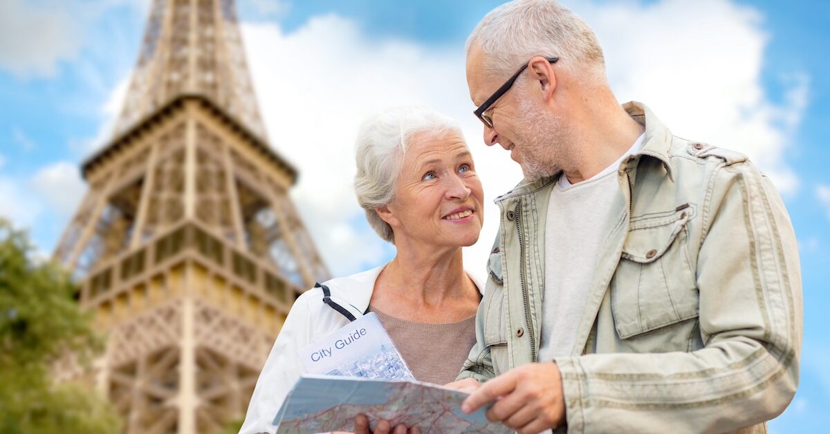 Senior couple with map and city guide over eiffel tower and blue sky background.