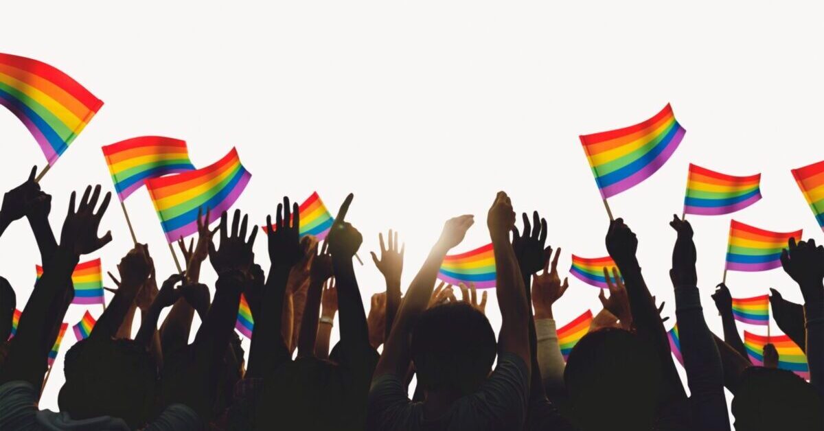 Hands in the air with the LGBTQ+ flag.