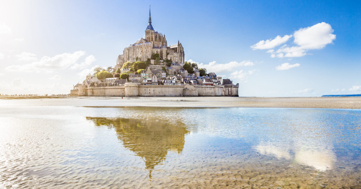 Panoramic view of famous historic Le Mont Saint-Michel tidal island on a sunny day with blue sky and clouds in summer, Normandy, northern France