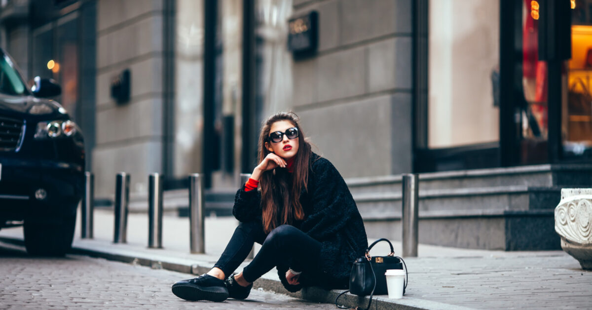 A person sitting on a sidewalk