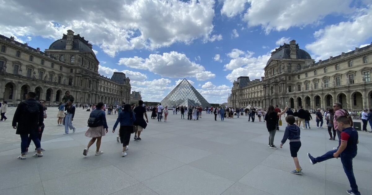 A group of people walking outside of Louvre