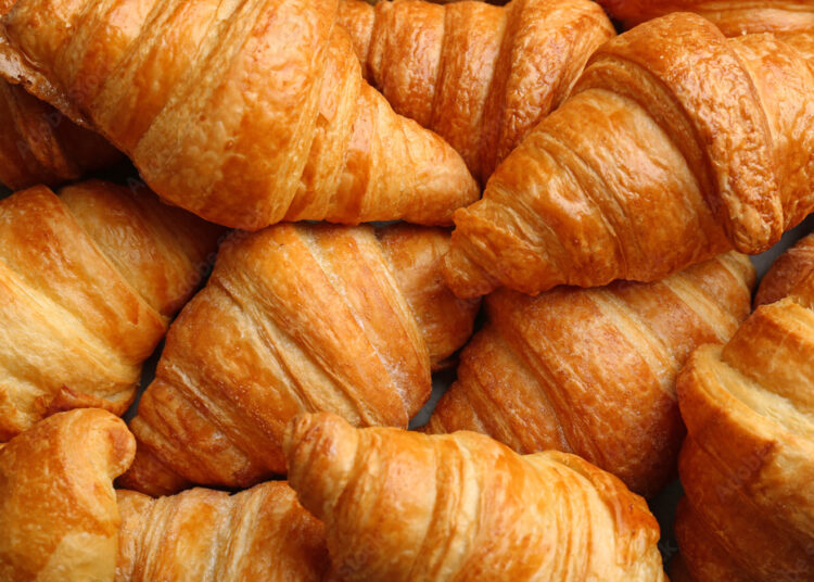 Fresh tasty croissants as background, closeup. French pastry