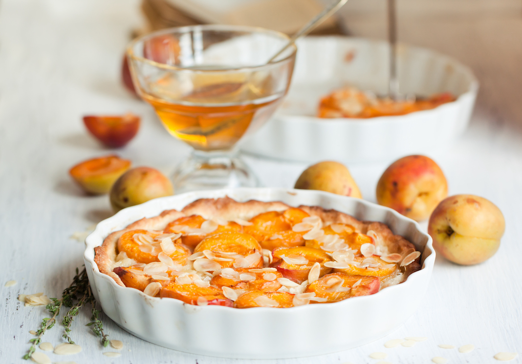 Breakfast with homemade apricot tart with almonds, fresh apricots and honey on white wooden table
