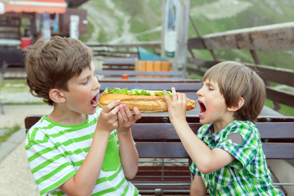 Two Kids Eat A Long French Bread In Summer, Shutterstock