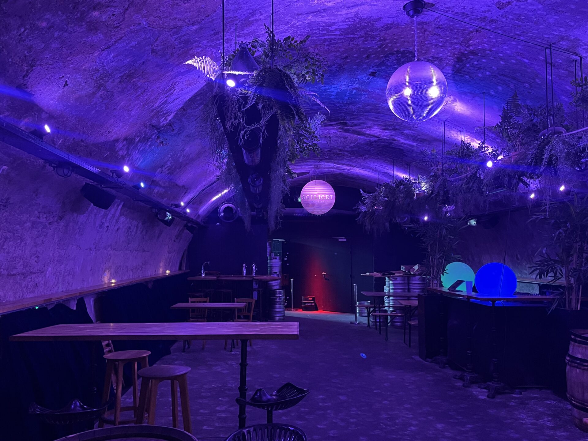 Underground bar with disco balls and neon lighting.