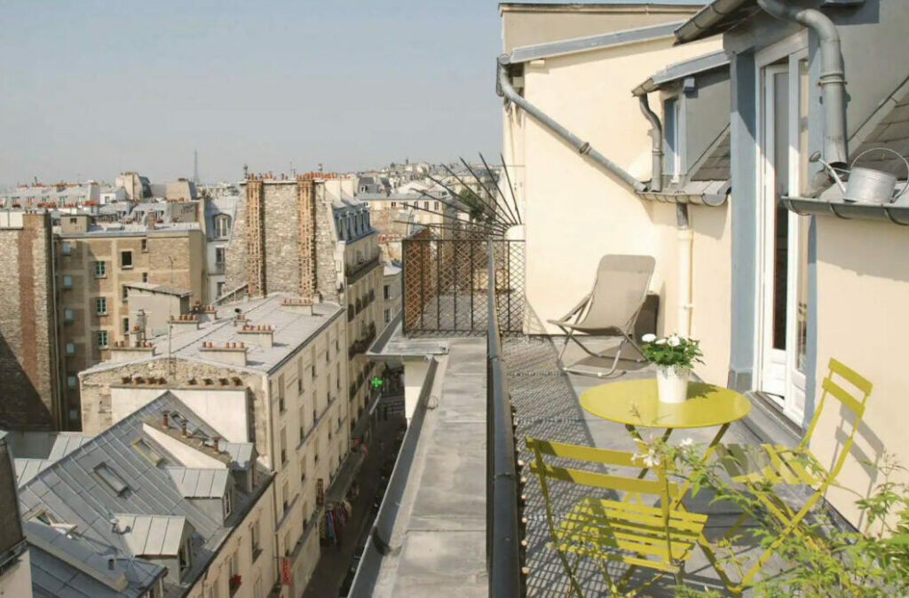 A terrace in Paris with a green table and chairs on the rooftop, Paris Airbnb.